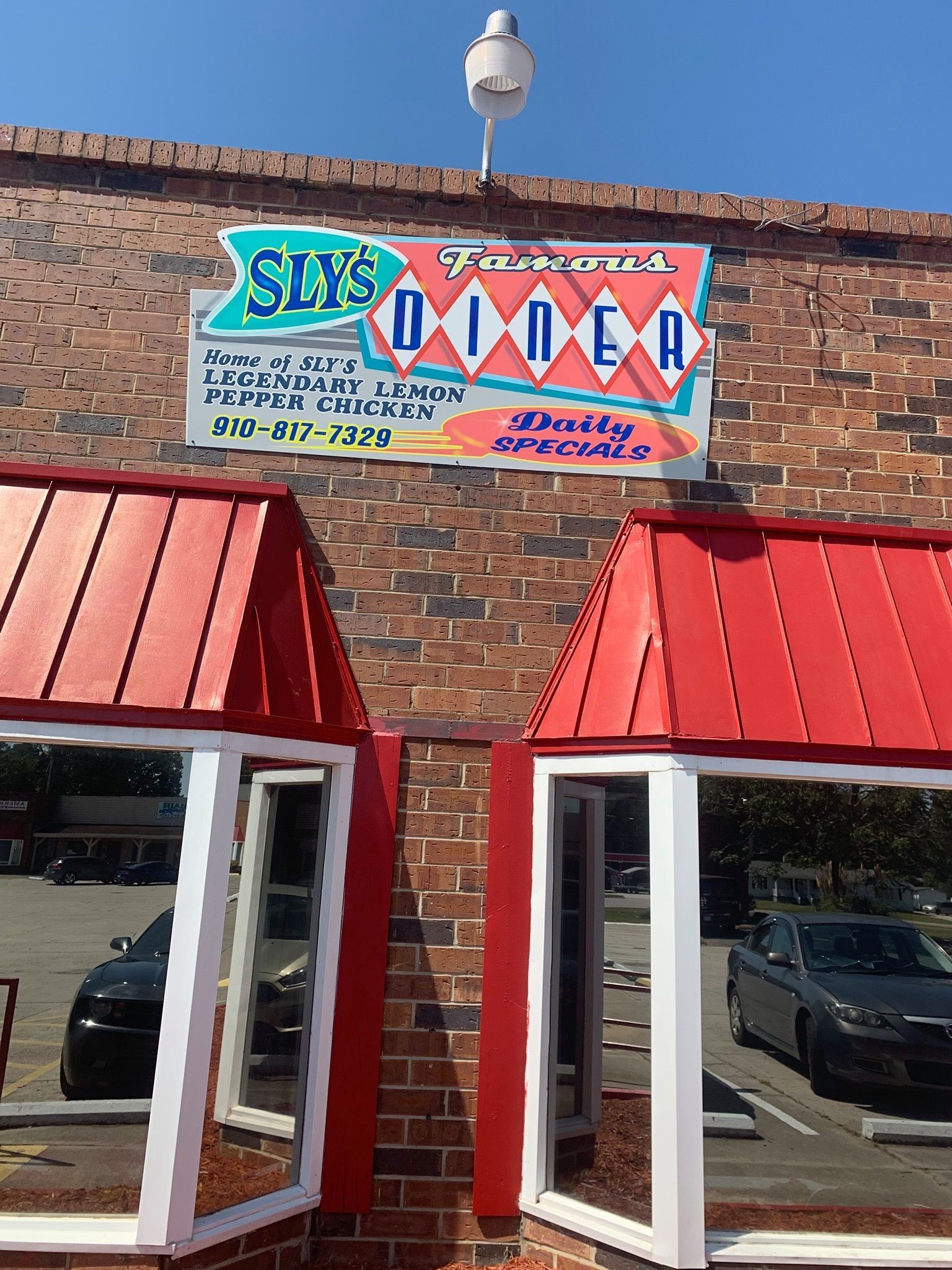 Sly's Diner restaurant with red and white signage, red roof, brick building, and parked cars.